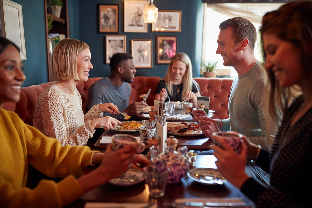 Group of diners enjoying food and conversation in a restaurant, showing how restaurant noise and a noisy restaurant atmosphere can affect acceptable noise levels in restaurants.